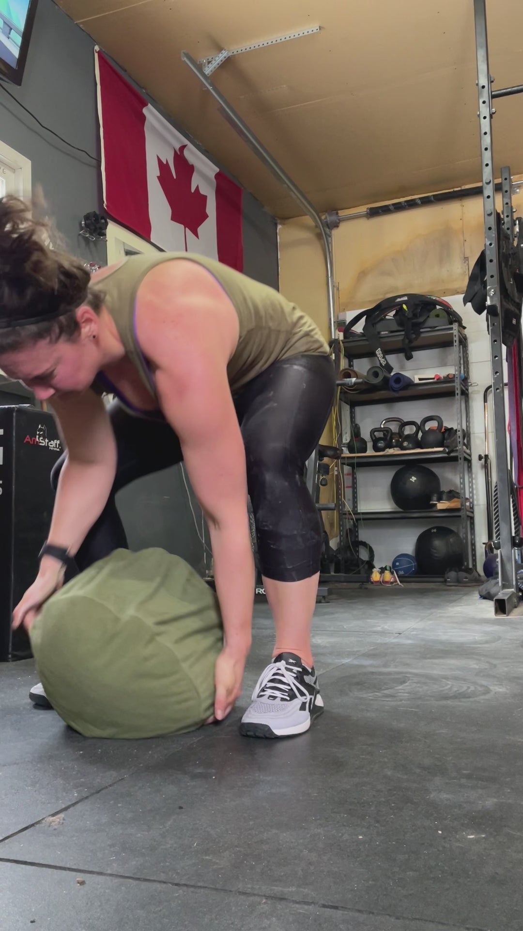 Female is tossing a 100lb Sandbag over her shoulder and throwing it behind her
